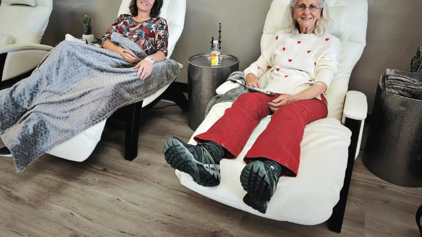 Two women under blankets in white recliners during IV drips at Alpha IV Therapy