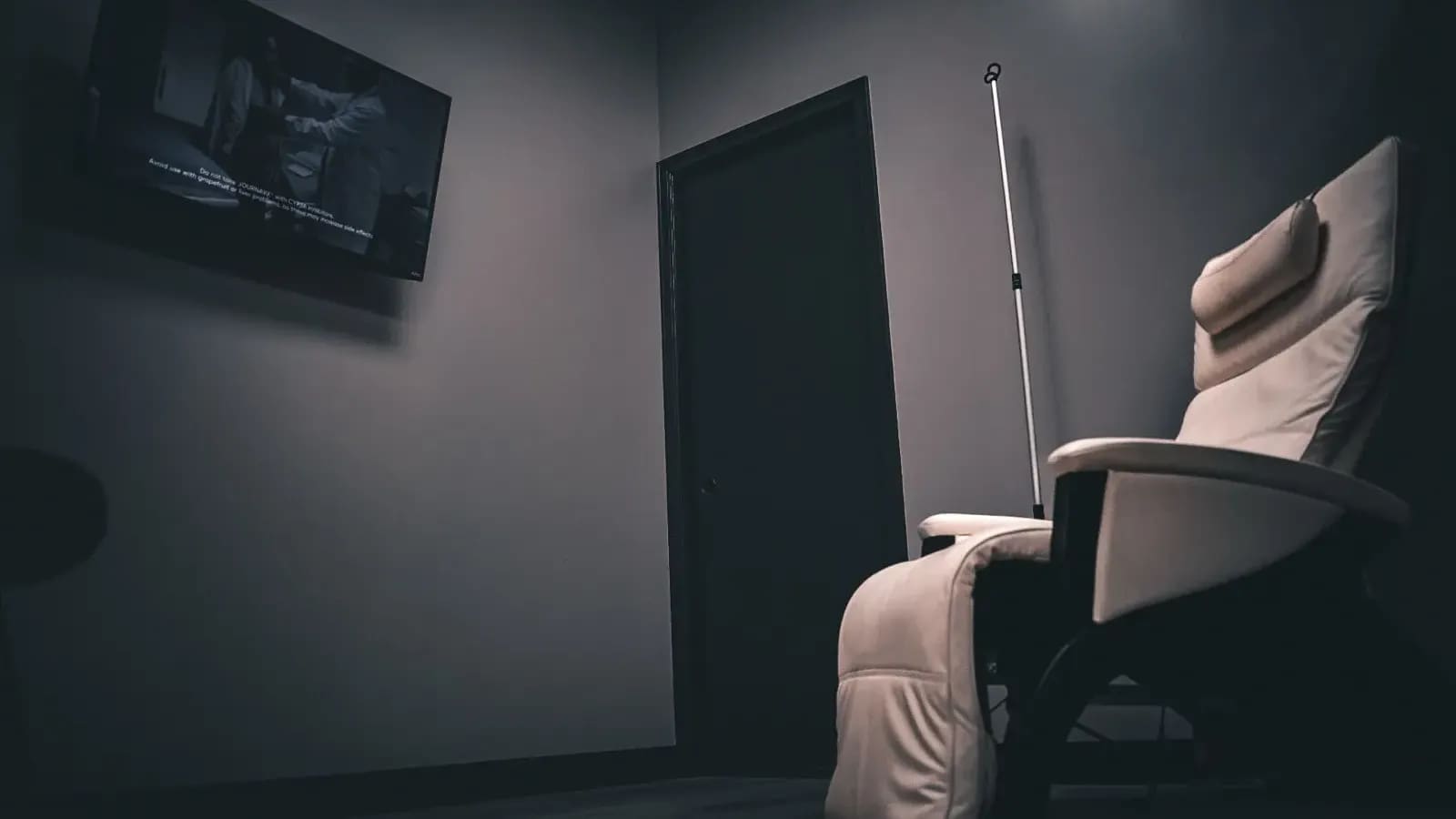 A single infusion recliner, IV pole and wall TV in a treatment room at Alpha IV Therapy
