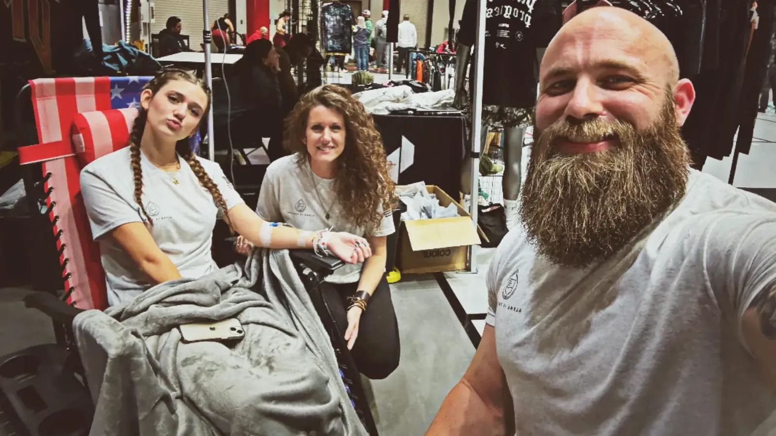 Selfie of an Alpha IV Therapy team member with two women receiving IV drips at an event